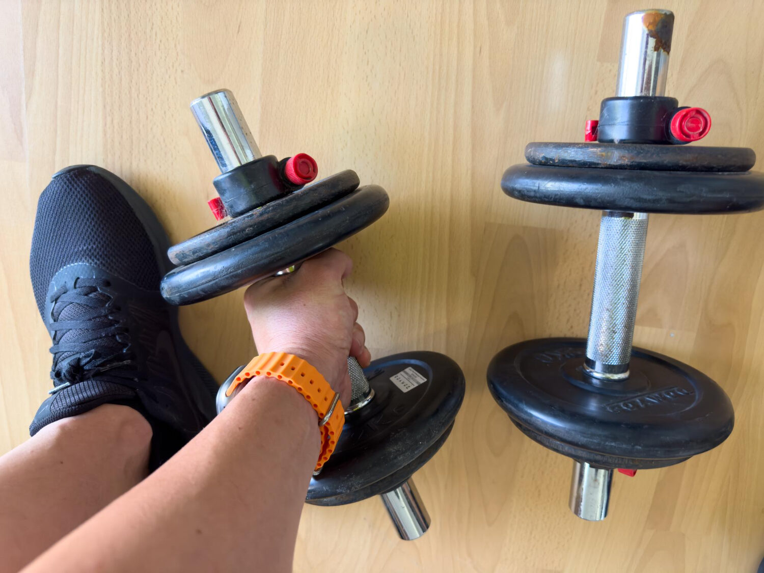 homem utilizando halteres ajustáveis em academia