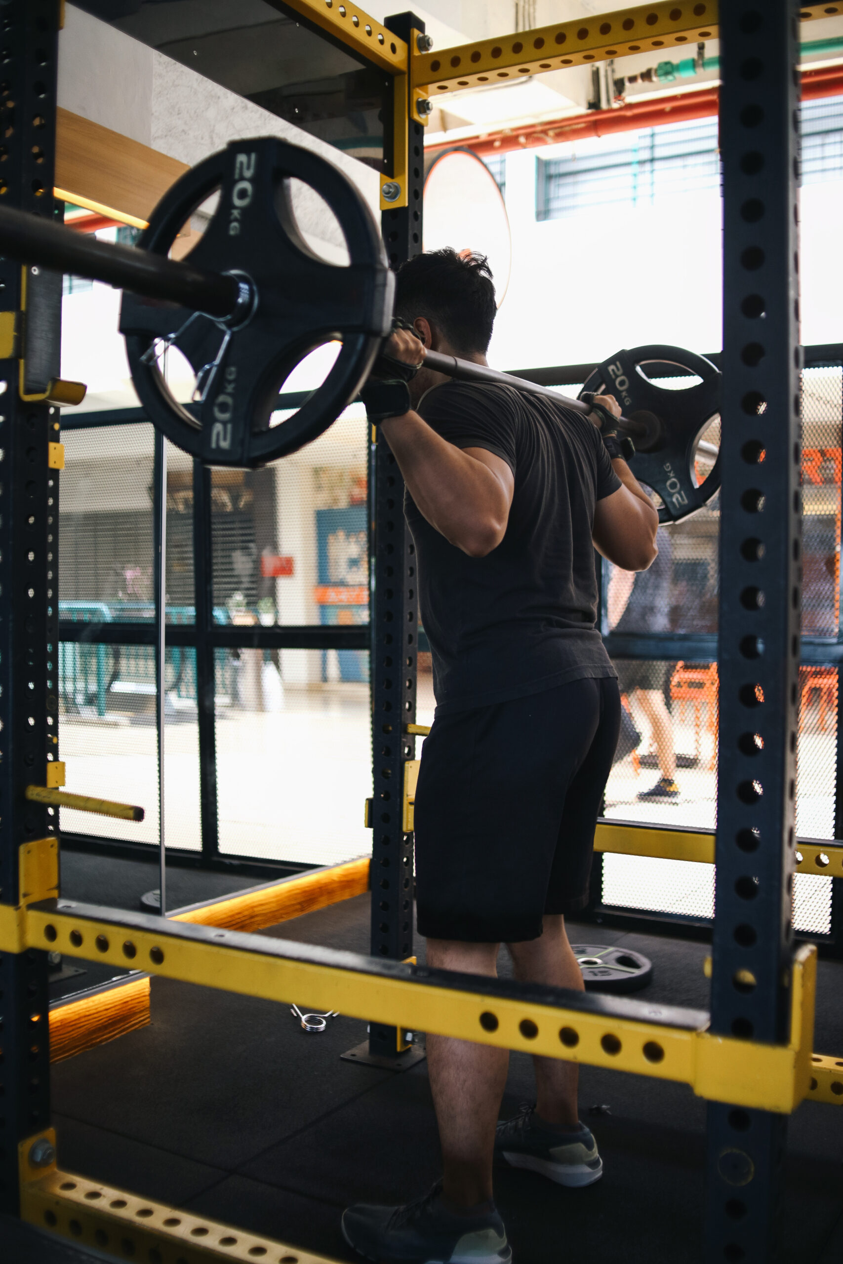 homem usando power rack em academia